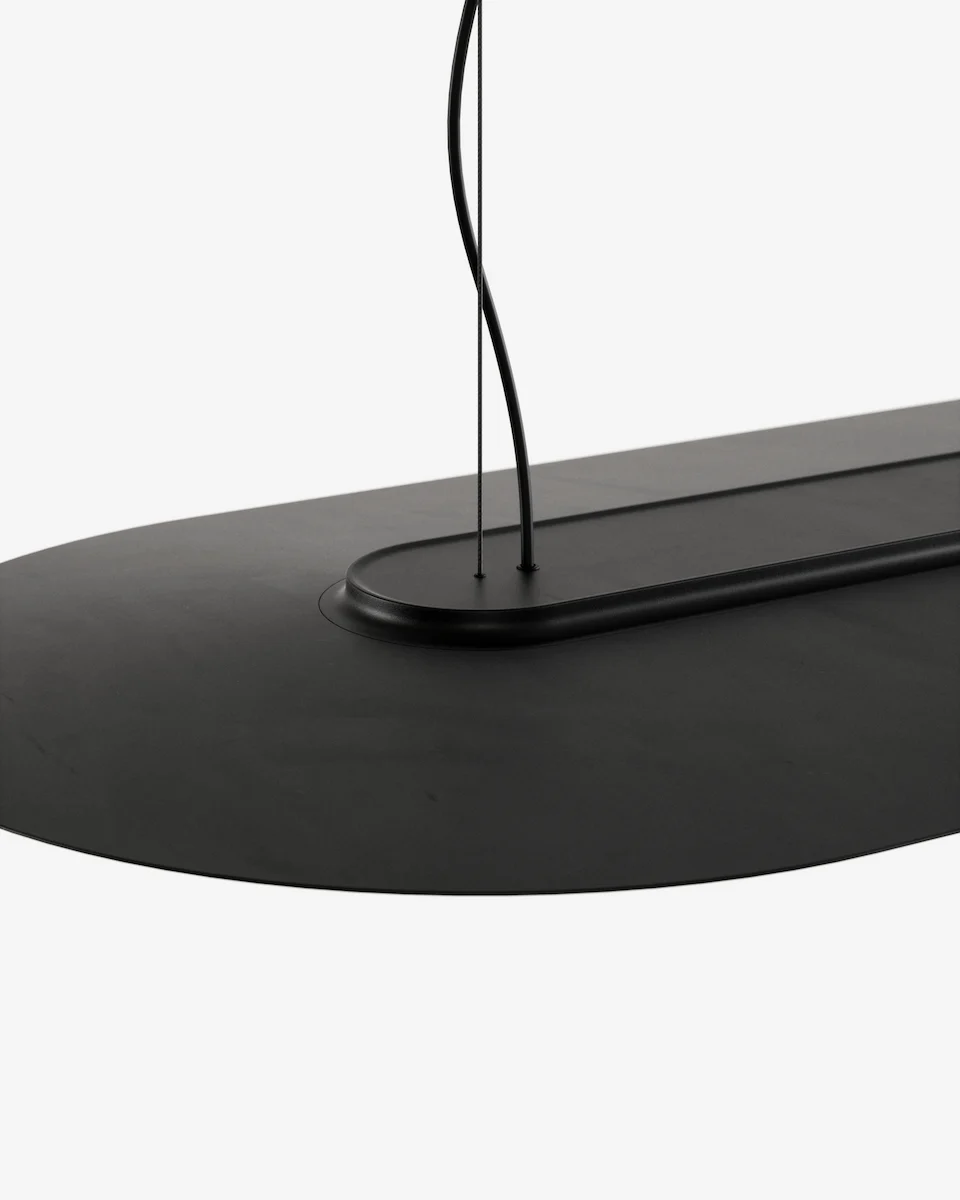 Helios elongated pendant light — detail shot of the matte black metal surface and architectural oval suspension fitting.